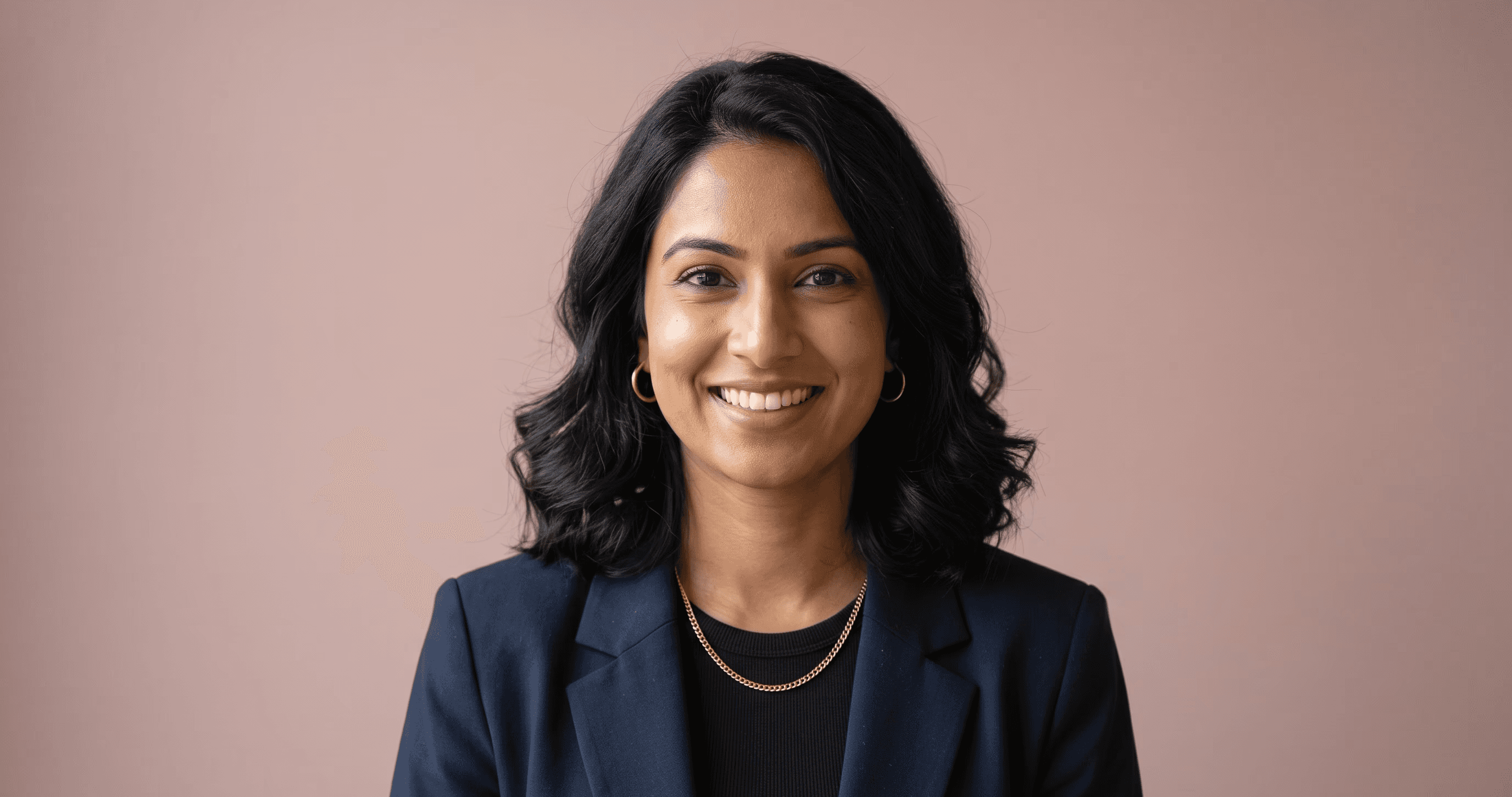 Portrait of Priya Nandakumar, Chief Product Officer, with red curly hair in a navy blazer