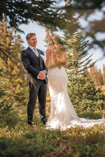 Tucker laughs as Clemmie reads from a sheet of paper in the forest clearing.