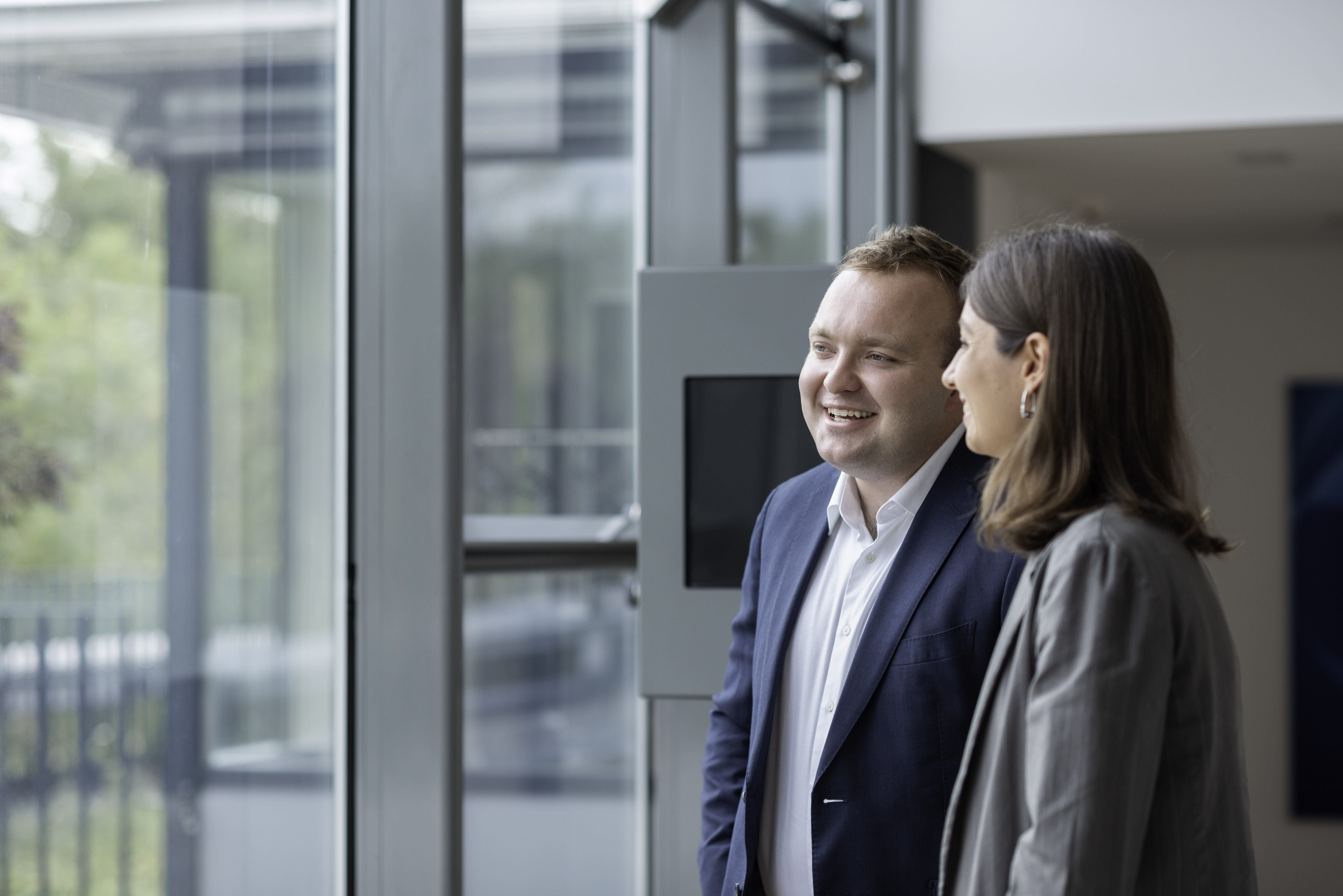 Two Team colleagues happily sharing a conversation by a window 