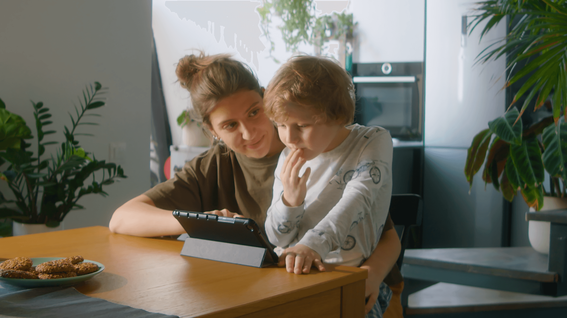 Woman helping her son on tablet.