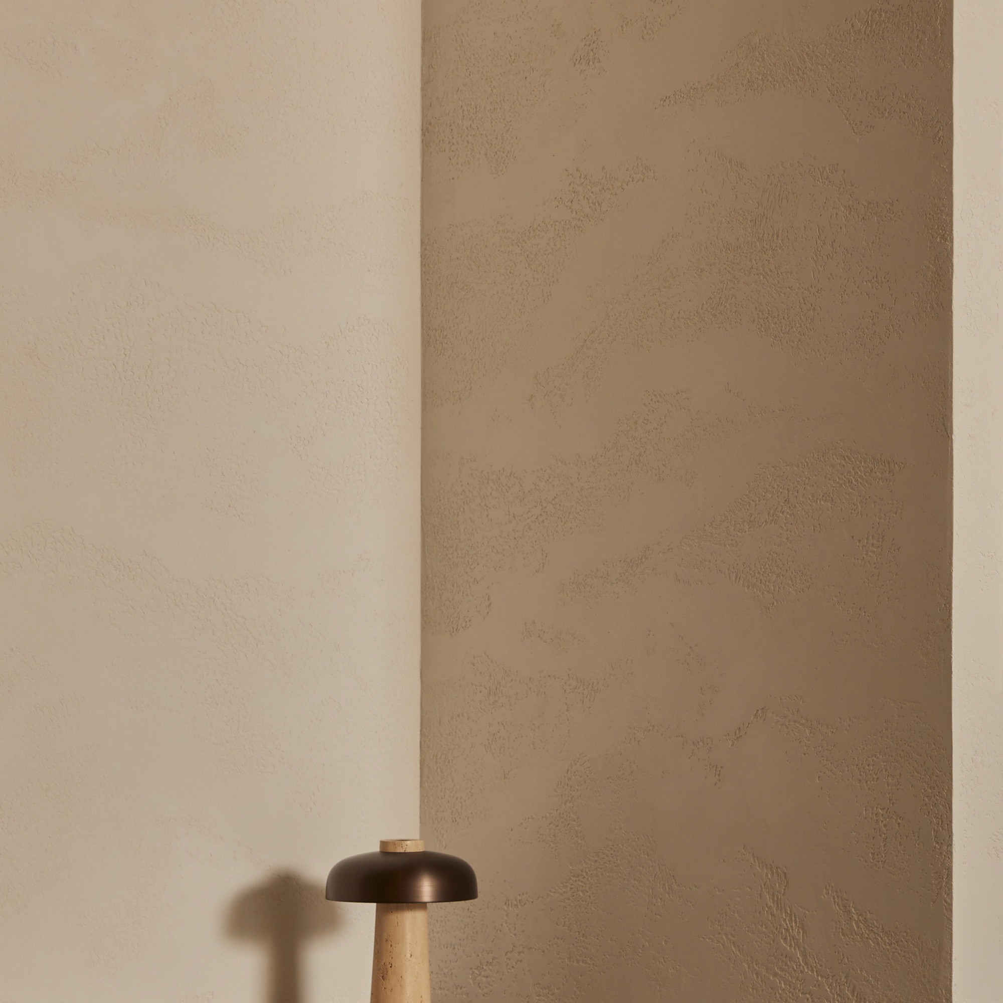Close-up of a corner where a smooth cream-plastered wall meets a textured limewash-finished wall
