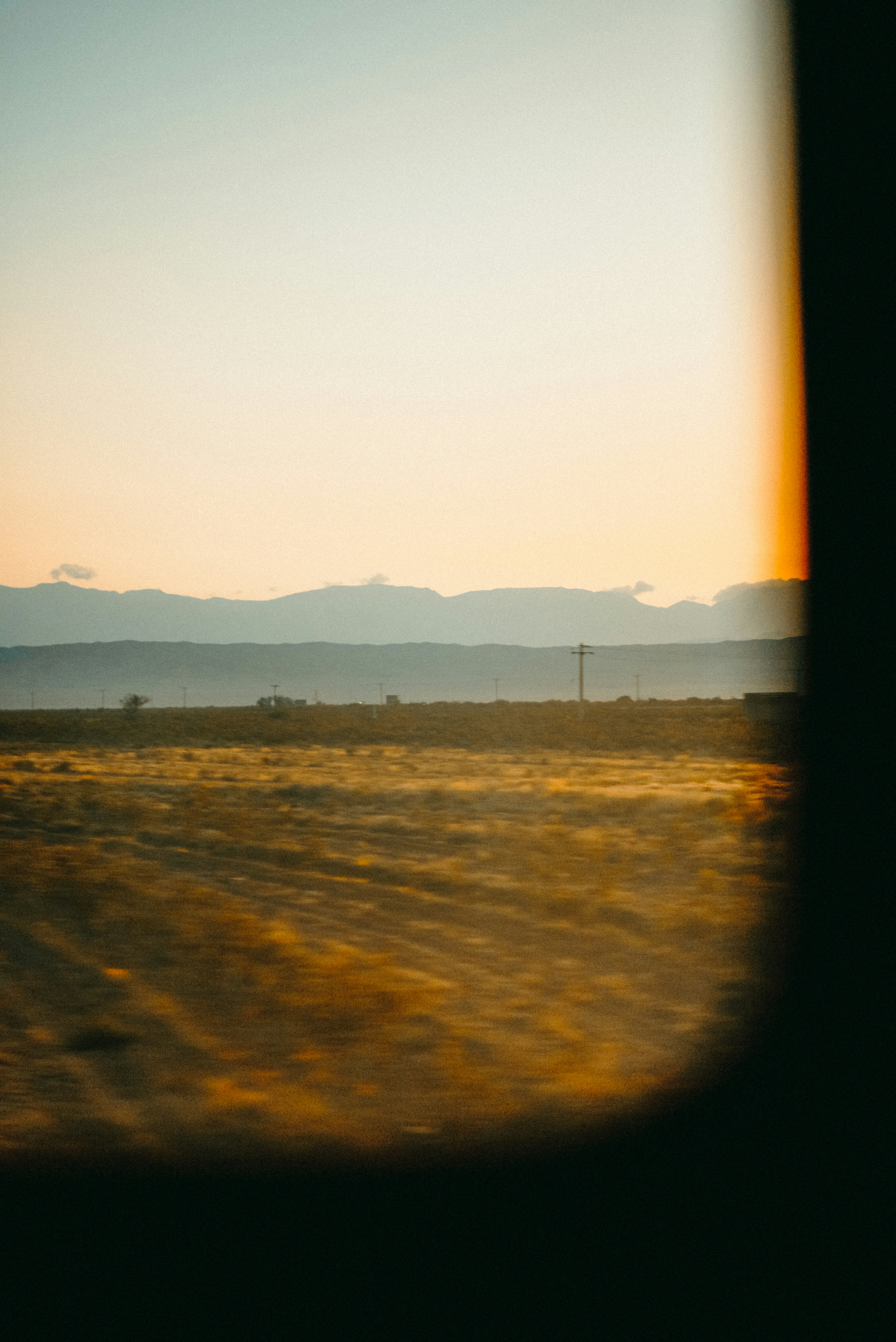 a field with a fence and mountains in the background