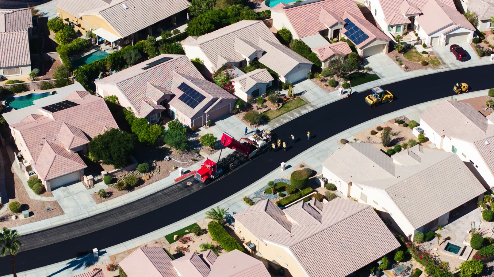 Zoomed-out aerial of asphalt crew paving new private roads for HOA