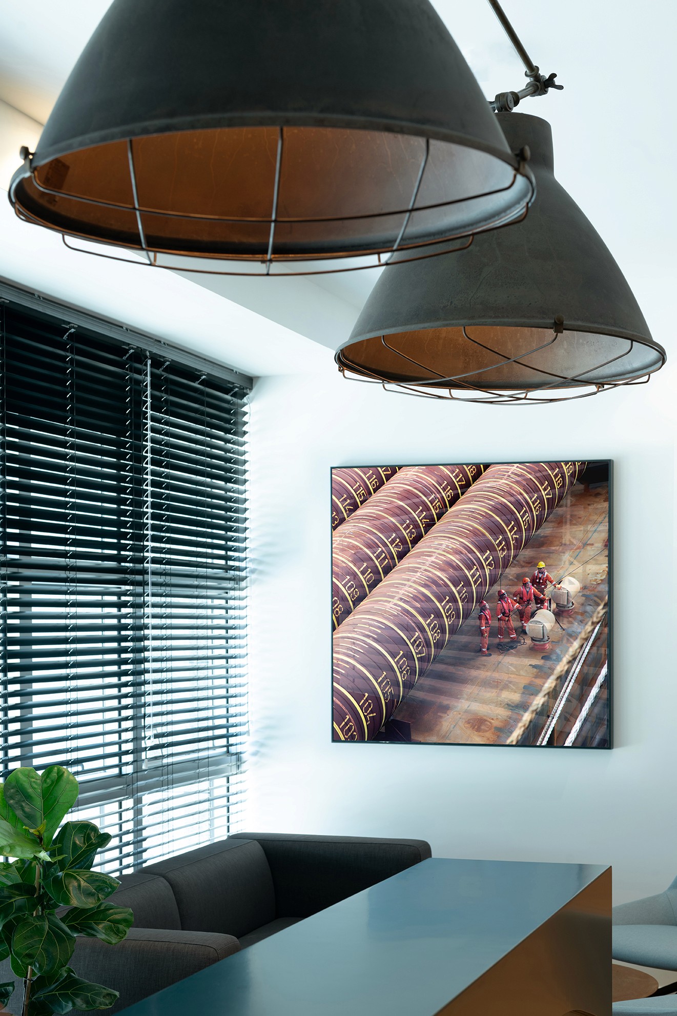 עיצוב משרדים מבוסס מיתוג: דלפק כניסה פיסולי בצורת הלוגו, המשלב צמחייה וניגודיות מול קיר האבן הטבעית