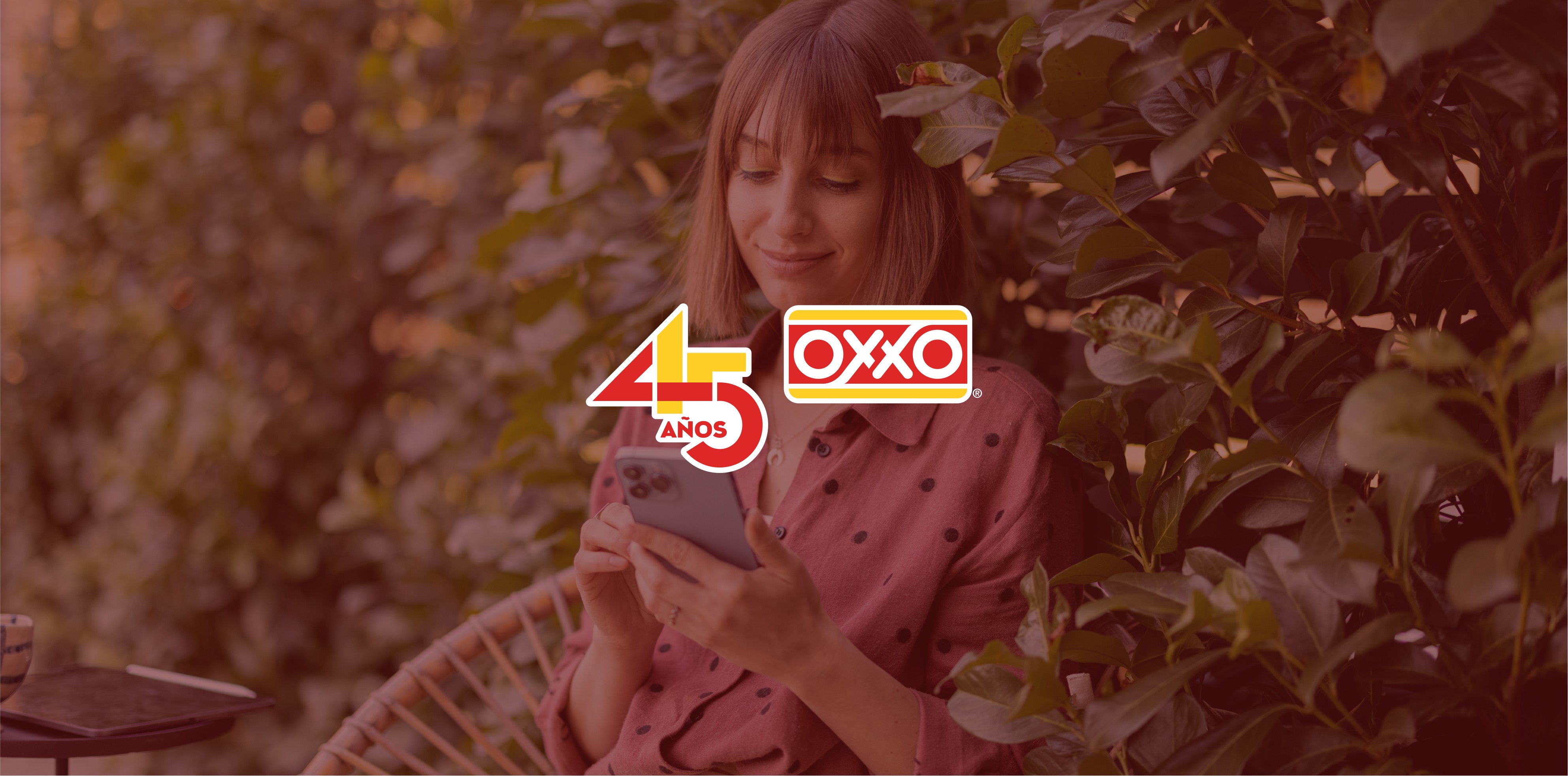 Smiling woman playing the OXXO loyalty game on her phone while sitting in a garden