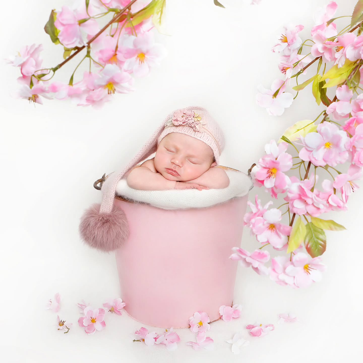 Sleeping newborn inside a pink bucket, captured in a creative newborn photoshoot in Dubai by Mahvin Photography.