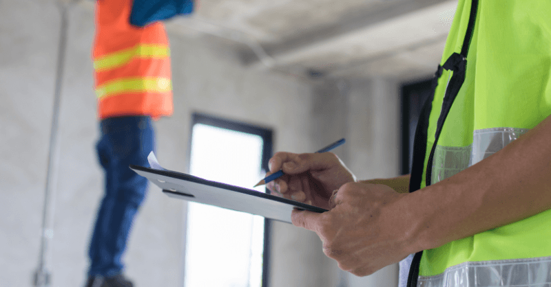 construction workers rebuilding the inside of a house, one has clipboard and pen, hands zoomed in
