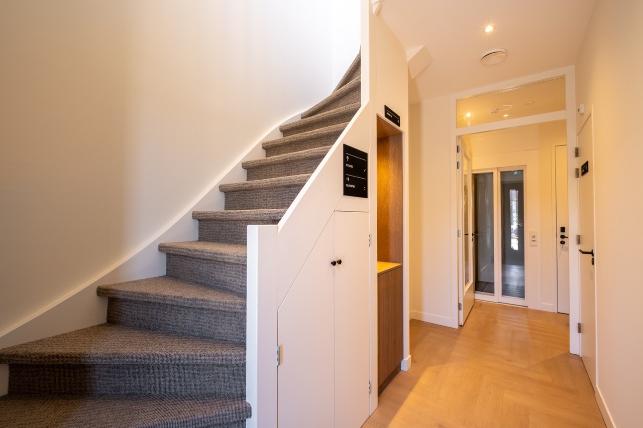 Trapopgang en gang van een boutique hotel in Scheveningen met warm hout en moderne verlichting.