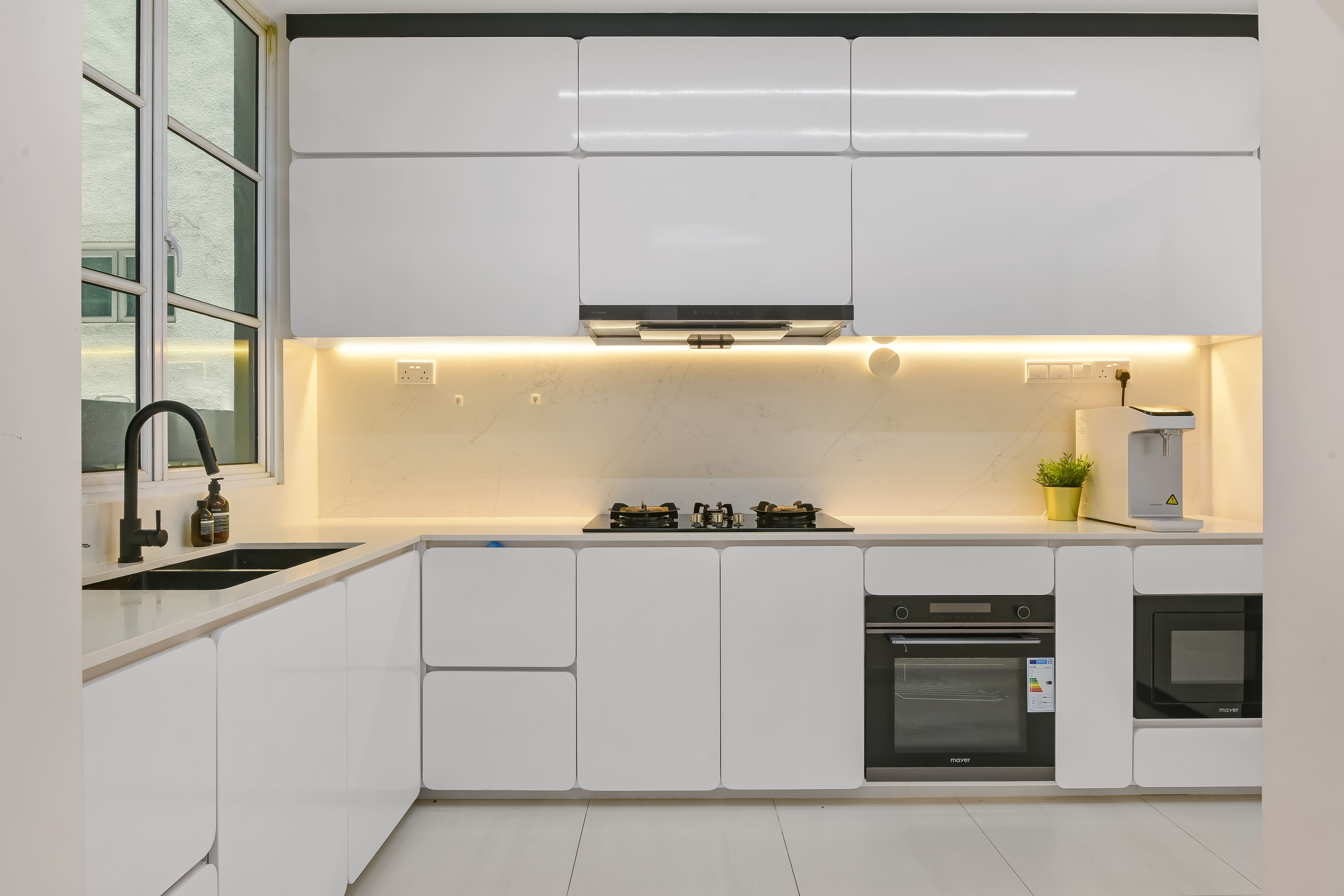 Sleek white modular kitchen with concealed cabinetry, integrated appliances, and ambient under-cabinet lighting for a clean, modern aesthetic.