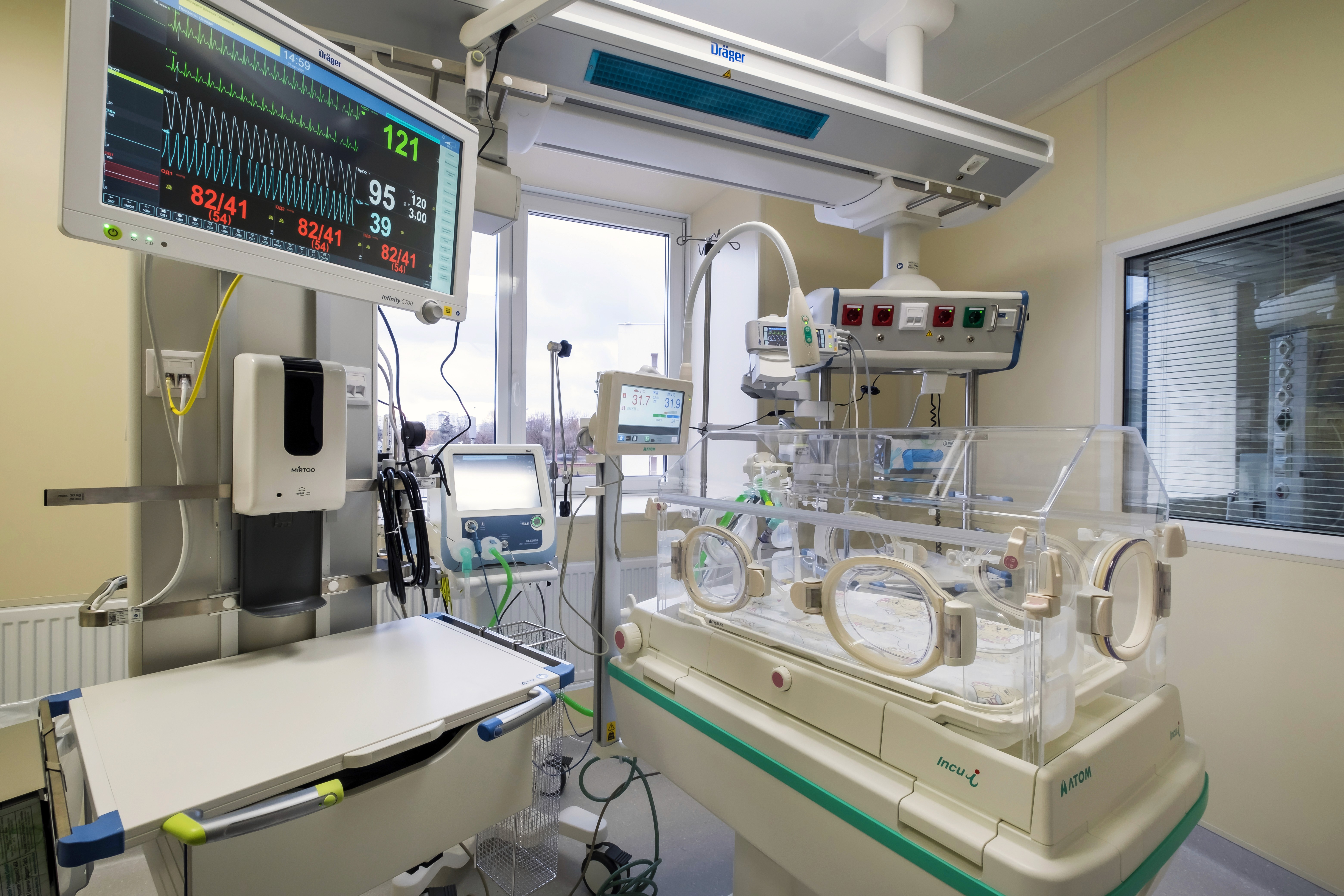 A modern neonatal intensive care unit with vital-signs monitor and incubator providing life-support care for premature infants.
