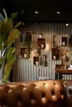 Gemütliche Lounge-Ecke im kAlps mit Ledersofa, Zimmerpflanzen und dekorativen Wandregalen.