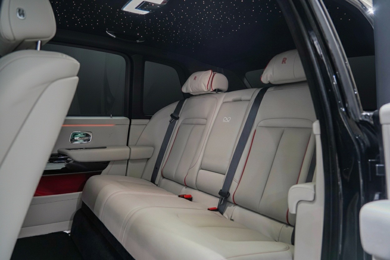 Rear seats interior of Rolls-Royce Cullinan Black Badge 2023, executive rear seating with white leather and red accents