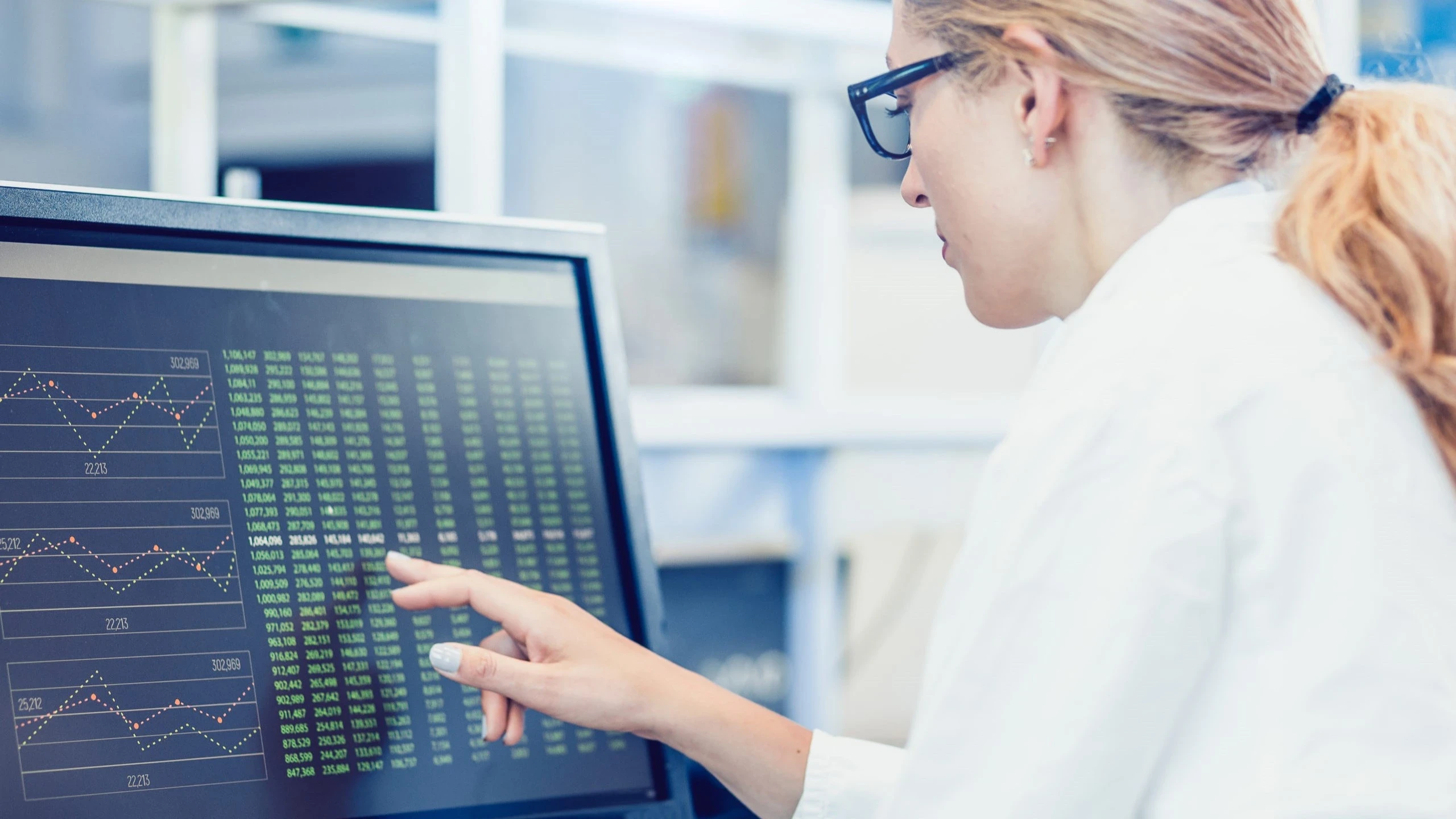 High school students in STEM research featured by a focused female scientist analyzing data on a computer screen in a RISE Research summer program lab setting.