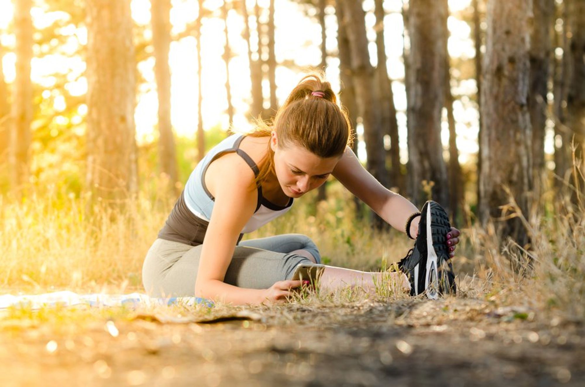 a woman stretching on the ground under the trees