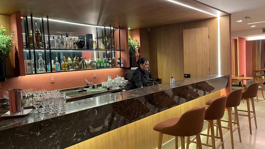 Garçom‑barista oferece espresso recém‑tirado em copo biodegradável, reforçando a hospitalidade sustentável do stand.