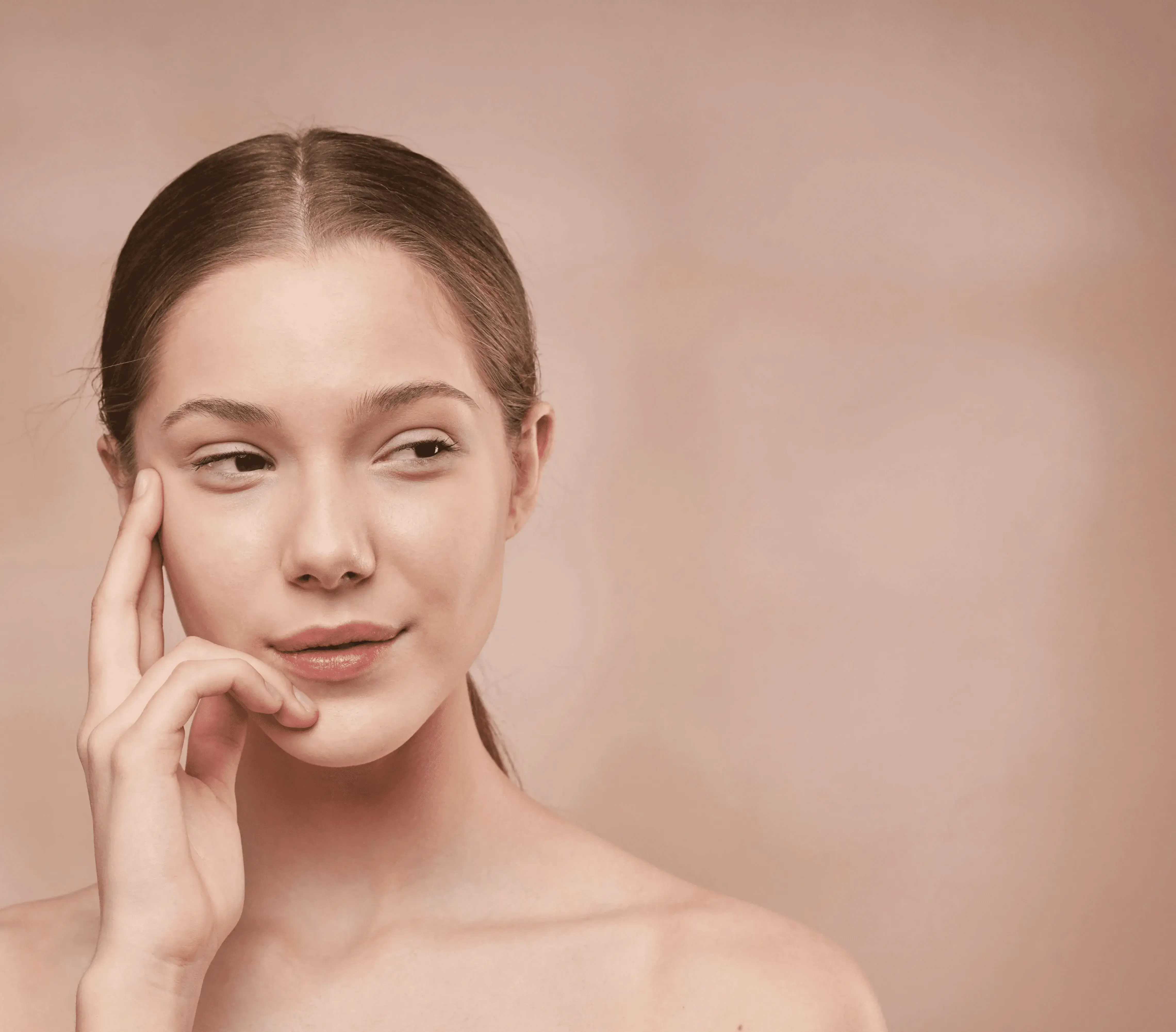 Young woman touching her face gently, representing rejuvenation and balance from personalized peptide and exosome therapy treatments.