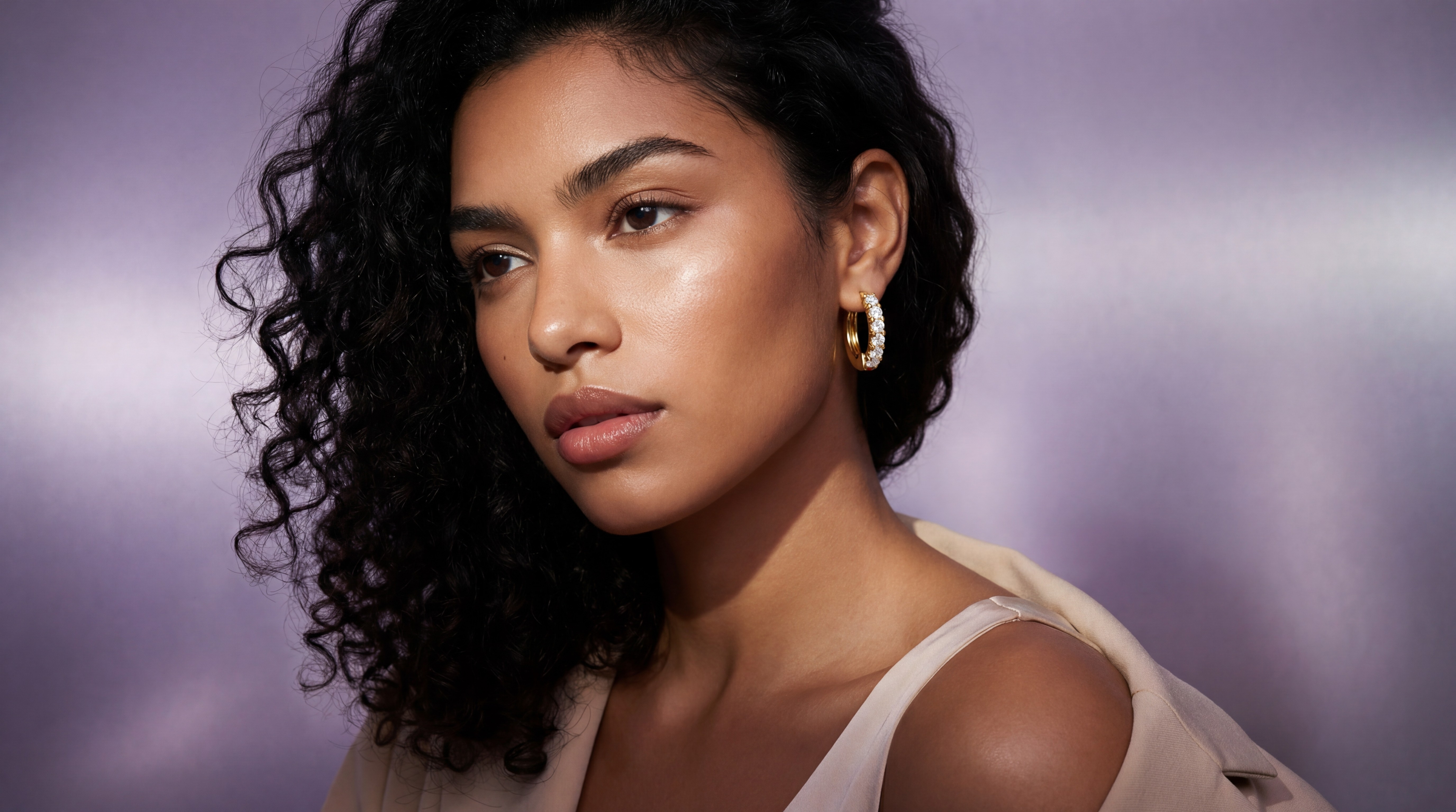 Woman wearing gold hoop earrings in a soft studio lighting setup, showcasing jewelry on a model