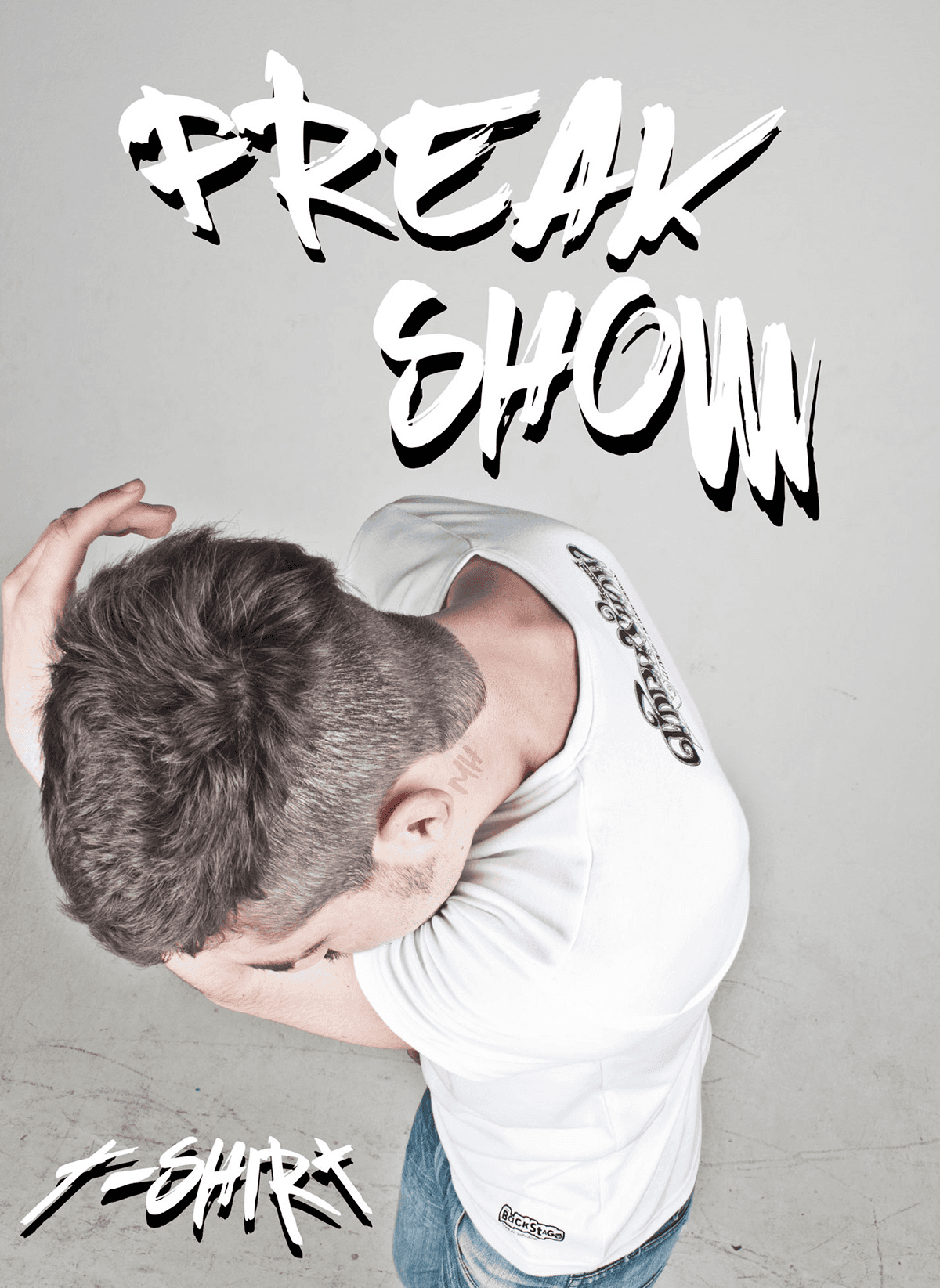 High-angle shot looking down at a man in a white t-shirt, emphasizing the "MH" tattoo on his neck. Large "FREAK SHOW" white brush-style text is positioned above him.
