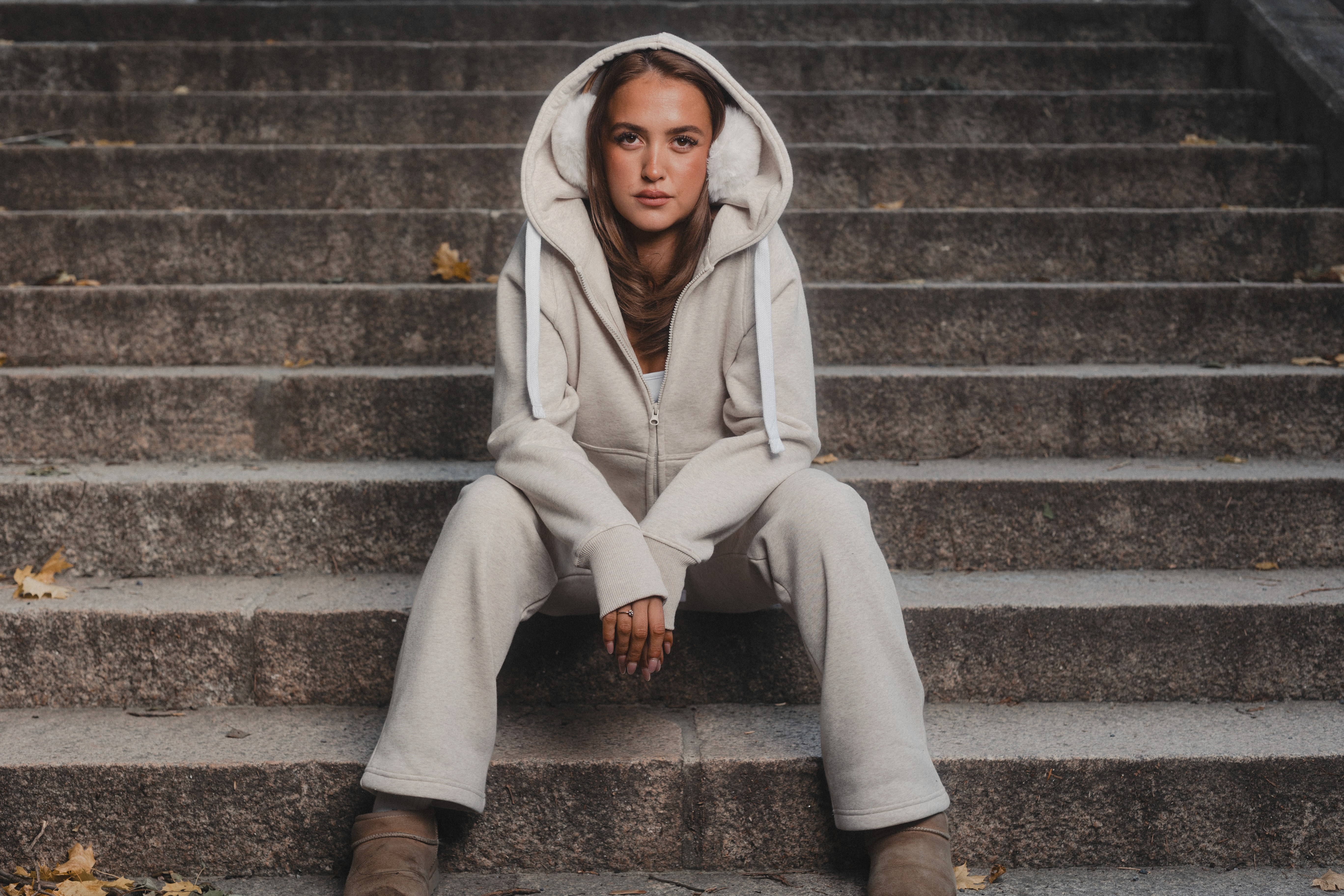 A model seated on stone steps wearing a full zip hoodie and sweatpants set, showcasing a complete loungewear look.