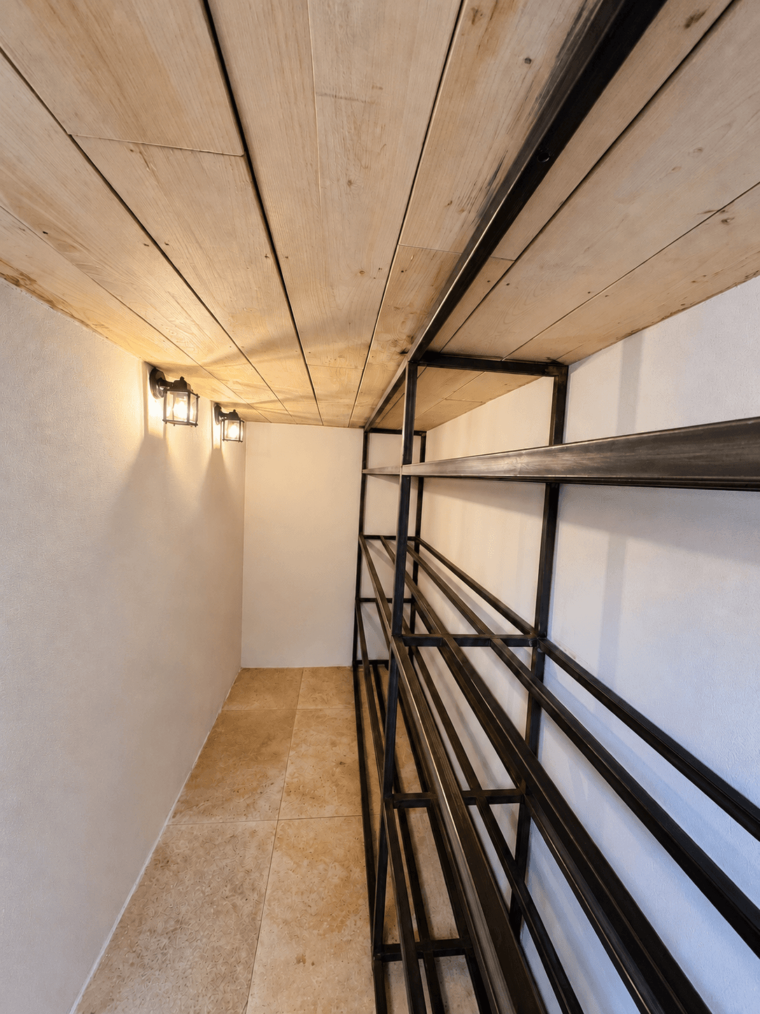 Intérieur de la cave à vin avec casiers métalliques sur mesure, murs clairs et plafond en bois