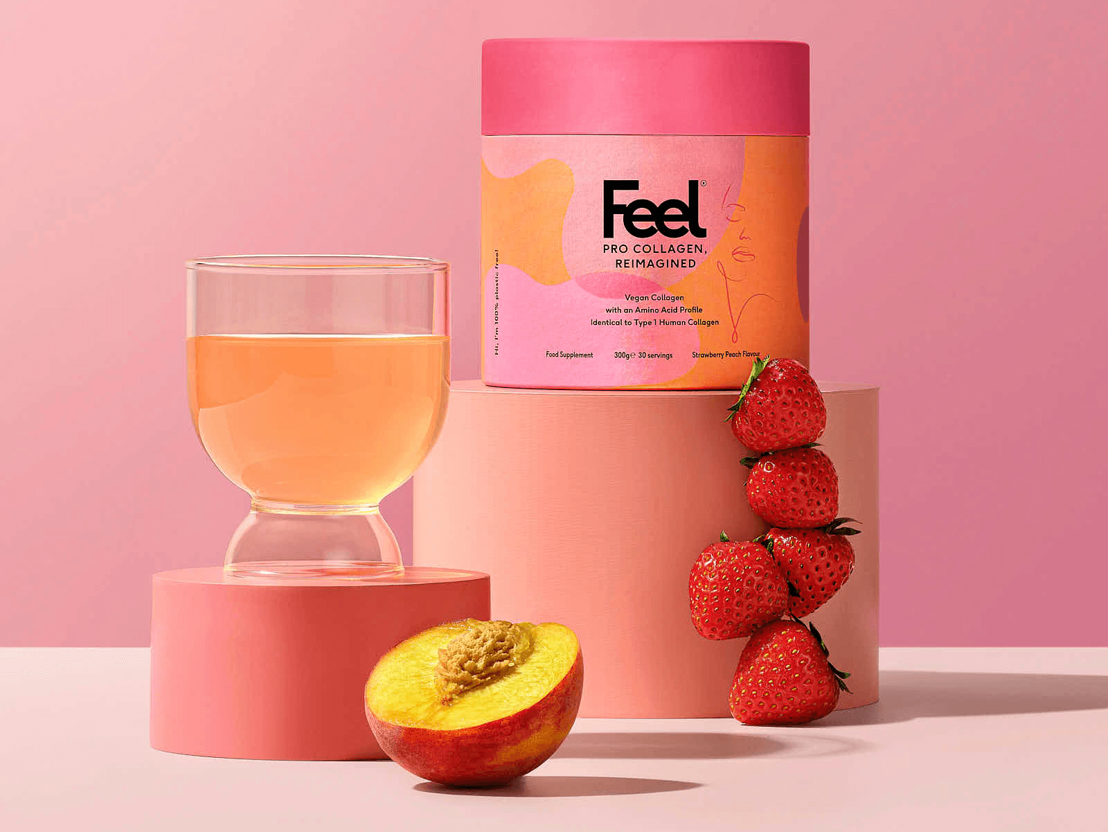 A pink-themed arrangement featuring a glass of drink, a container, and sliced peach and strawberries.