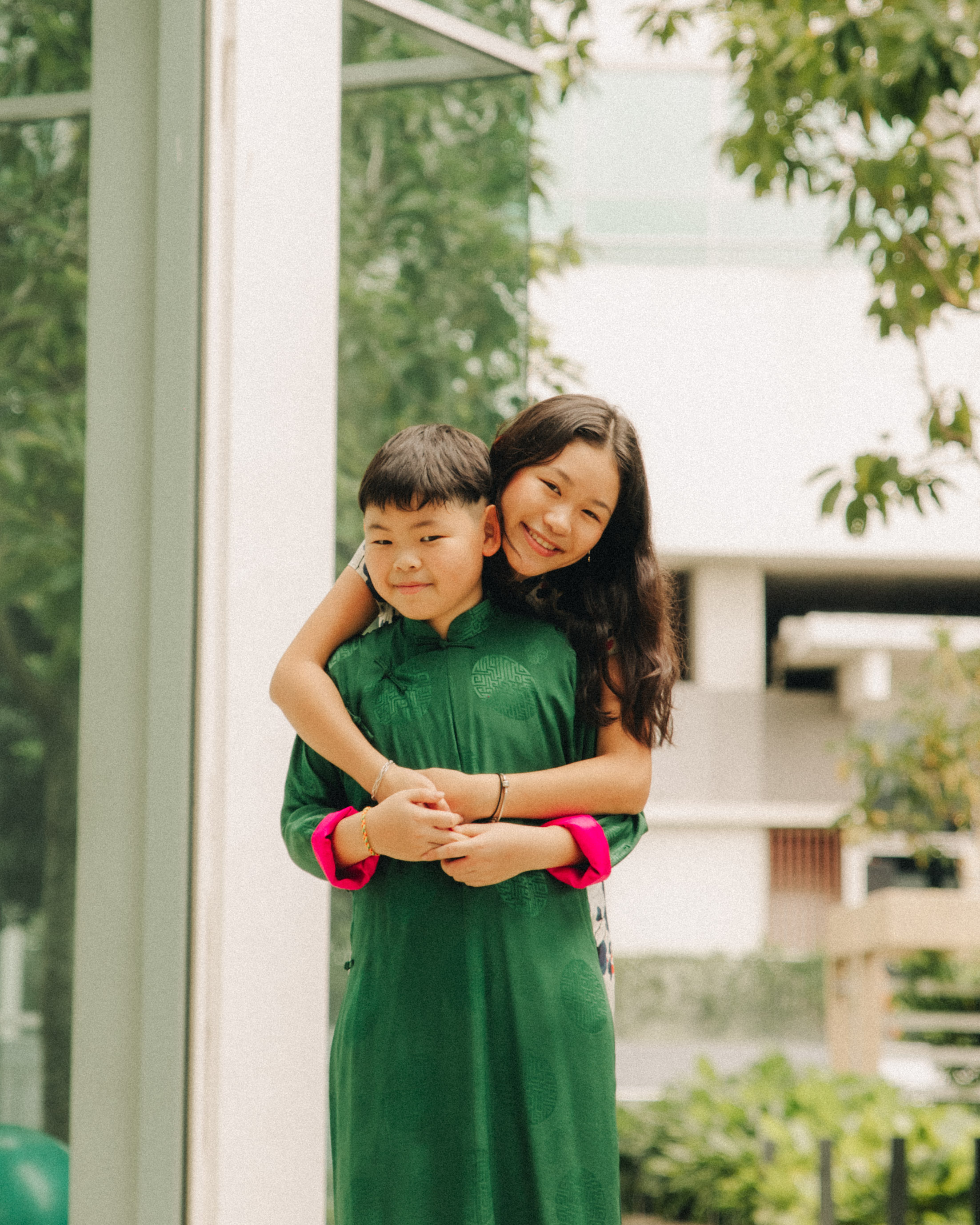 Siblings laughing together during a Chinese New Year garden photoshoot in Singapore