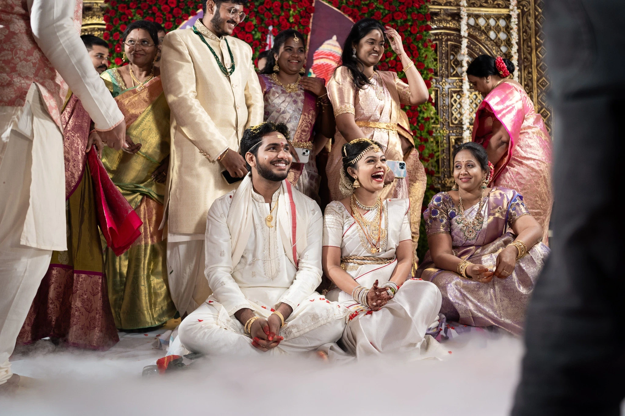 Lovely and Rohit share a joyful smile with their family during a stunning wedding ceremony in India. Captured by Out of The Blues, Fine Art Wedding Photography in Hyderabad.