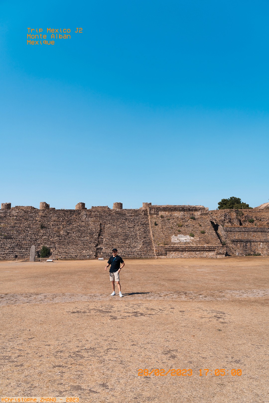 Homme explorant le vaste site archéologique de Monte Albán sous un ciel bleu.