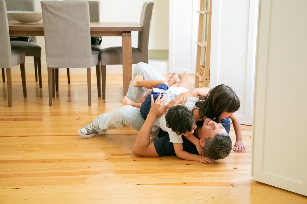 Dad playing on warm timber floors with young children, showing durable, family-friendly flooring designed for everyday Australian homes.