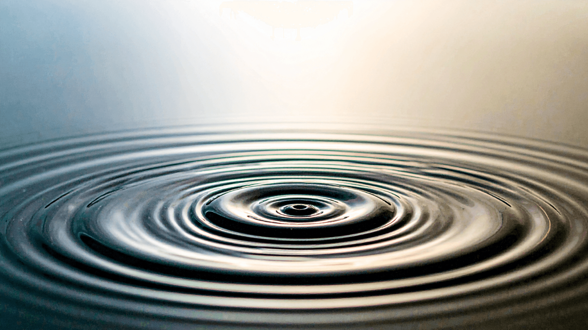 A winding road cuts through rocky terrain, surrounded by patches of green grass and illuminated by sunlight.