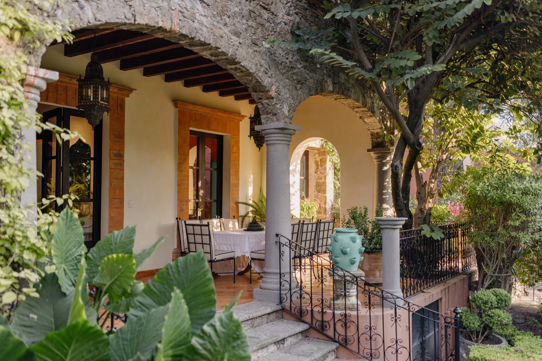 La Residencia San Miguel covered veranda with arched columns, mosaic tile table, and garden view