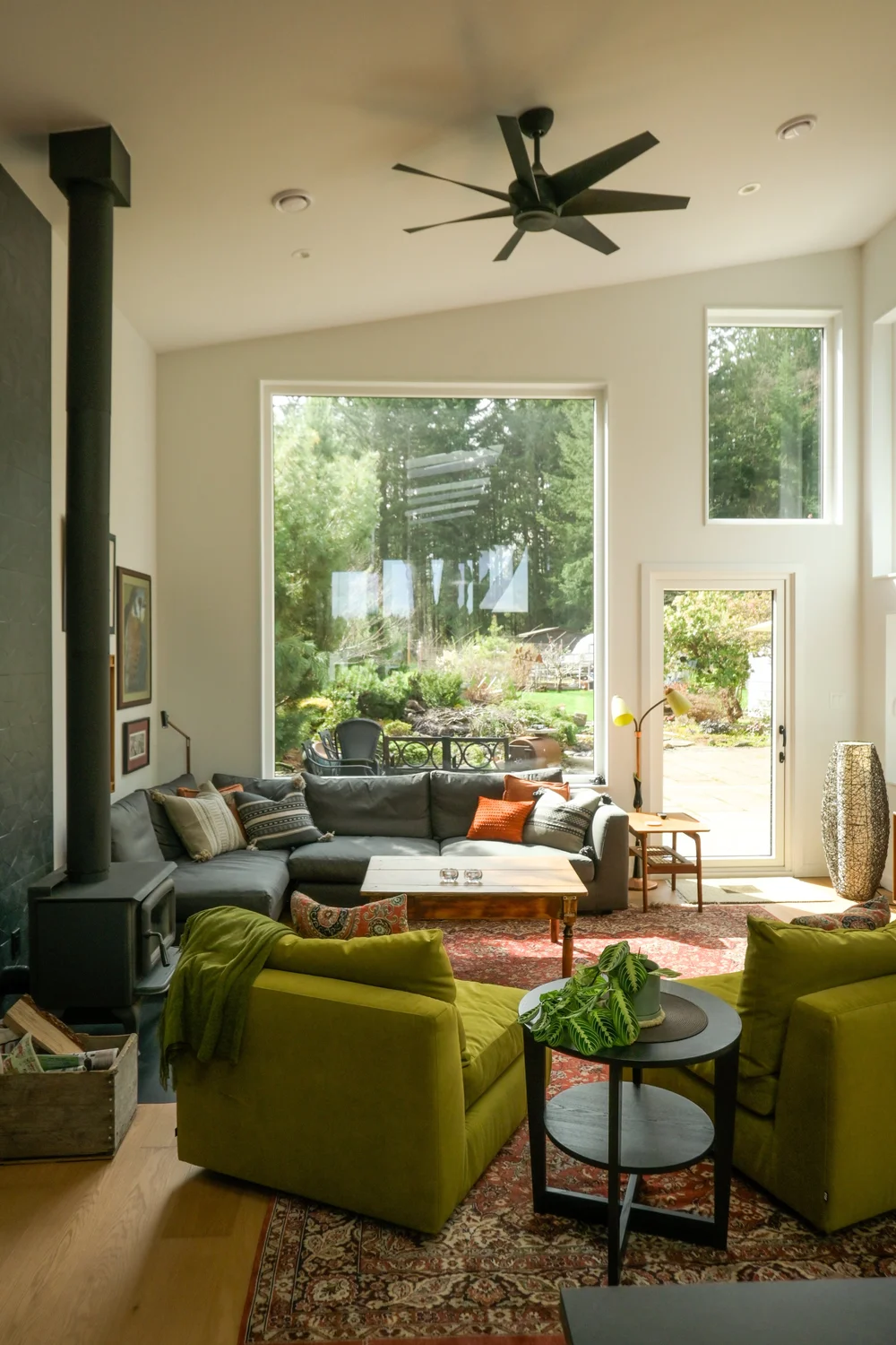 Modern two-story home with large glass windows, warmly lit interiors, and a balcony. Surrounded by trees and a manicured lawn at dusk. Cozy ambiance.