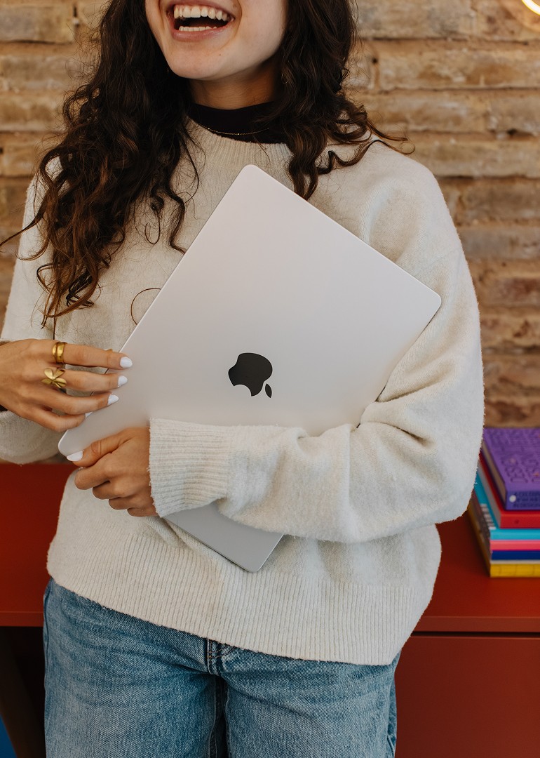 A laughing woman holding a MacBook