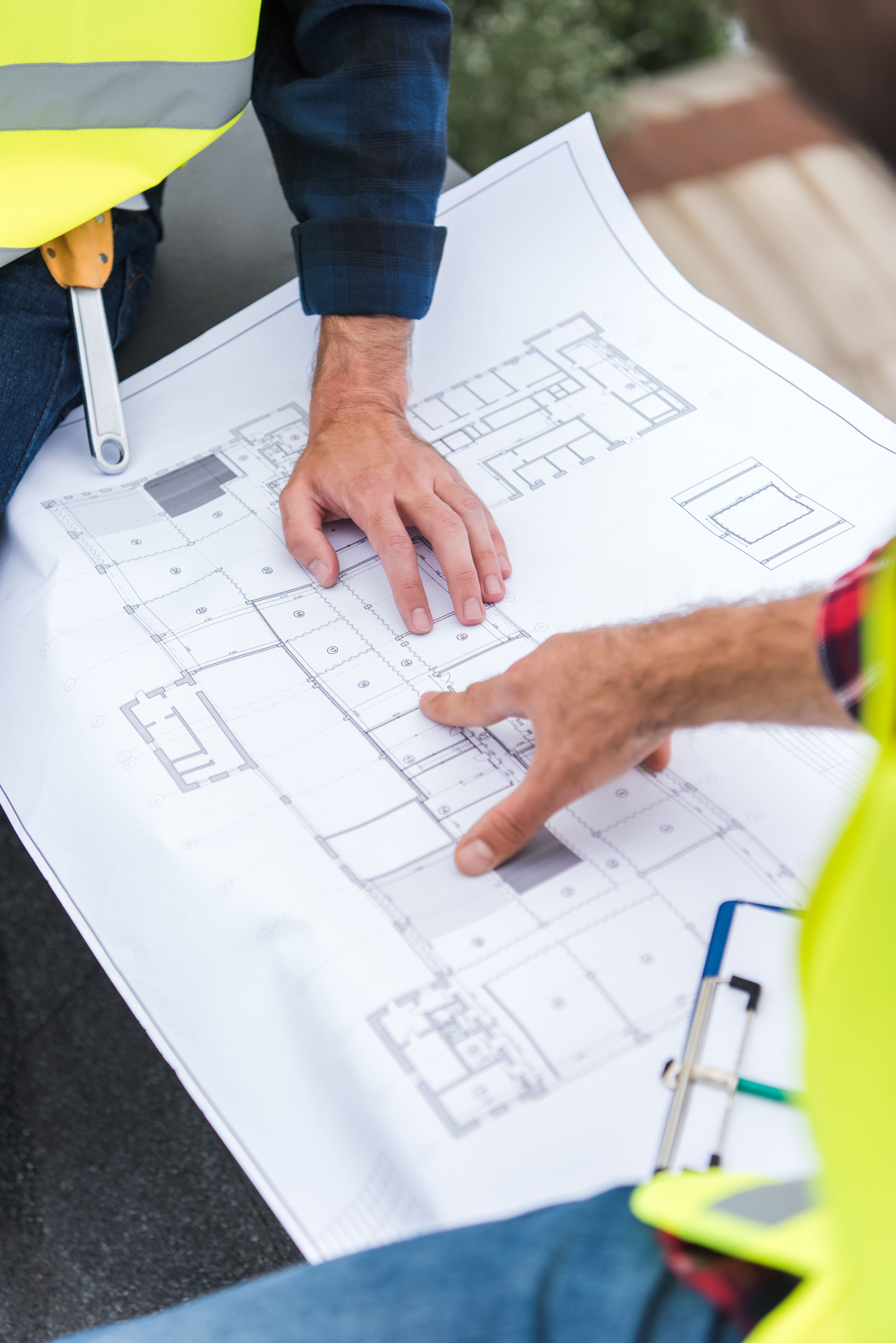 Detailansicht eines Bauplans mit zwei Händen, die darauf zeigen
