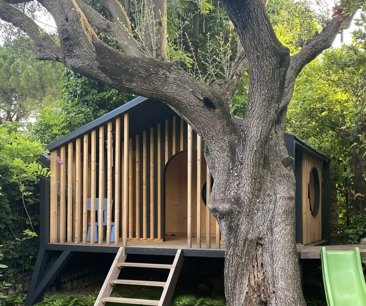 Cabane enfant Paris Copacabanon installée au Cannet, deux enfants assis devant la structure en bois