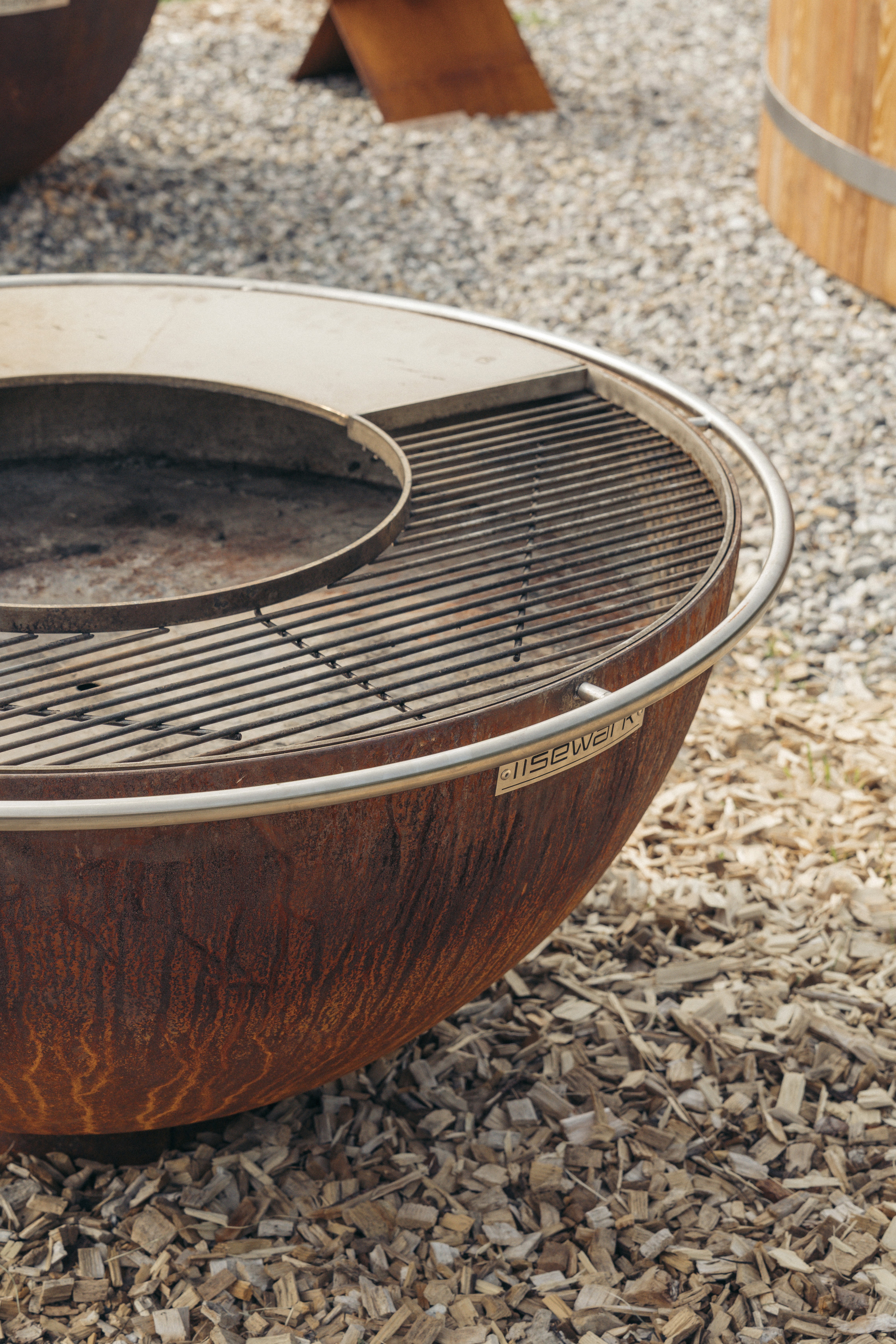 ahaufnahme eines runden Grills mit Metallrost, auf dem ein Spieß liegt.