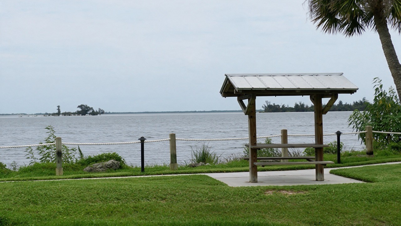 A covered picnic shelter on the grass at the water's edge