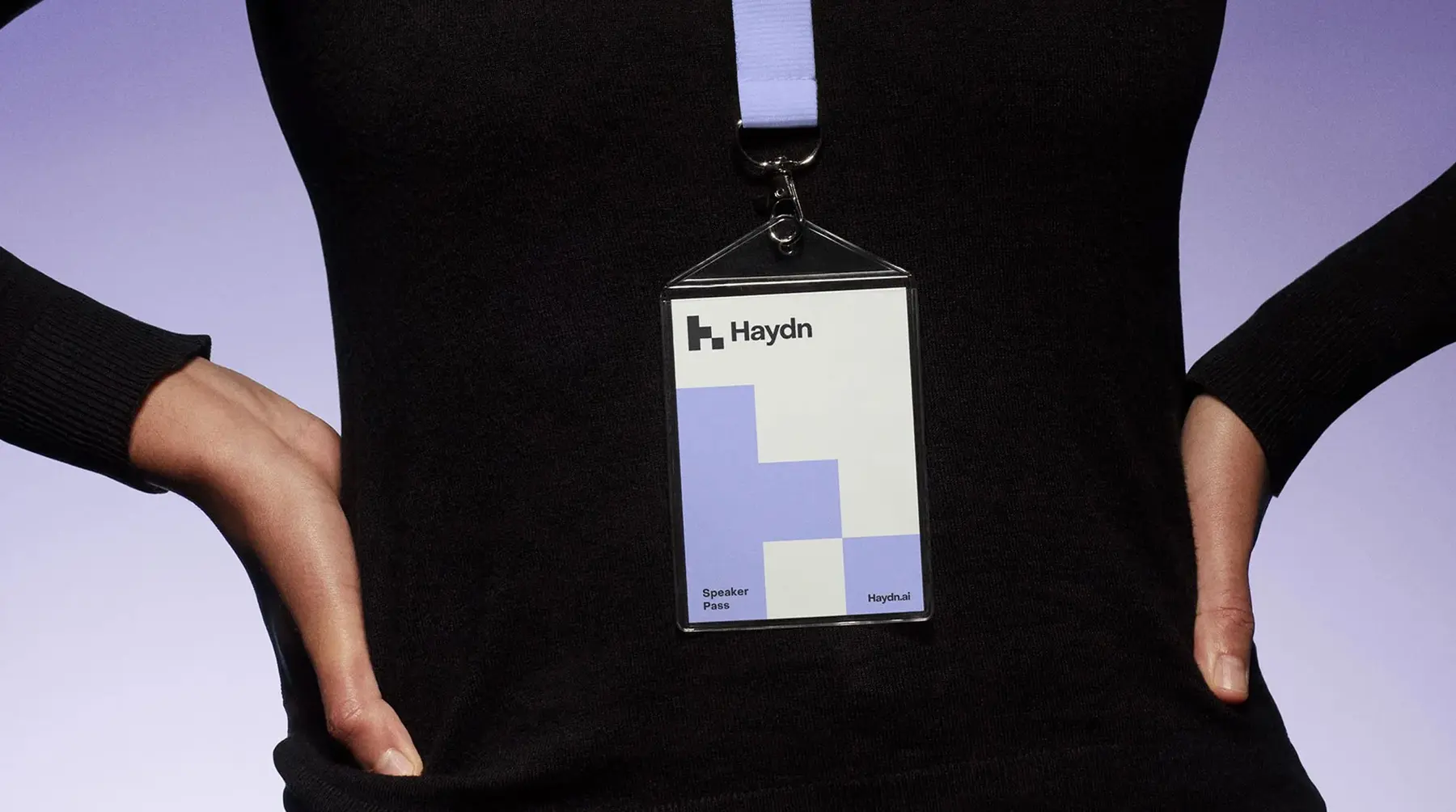 Haydn lanyard badge with lilac block logo worn over a black top