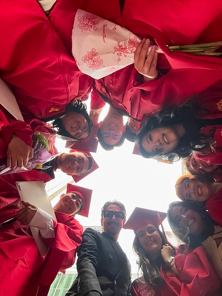 a group of people in commencement gowns looking down at the camera which is pointing up