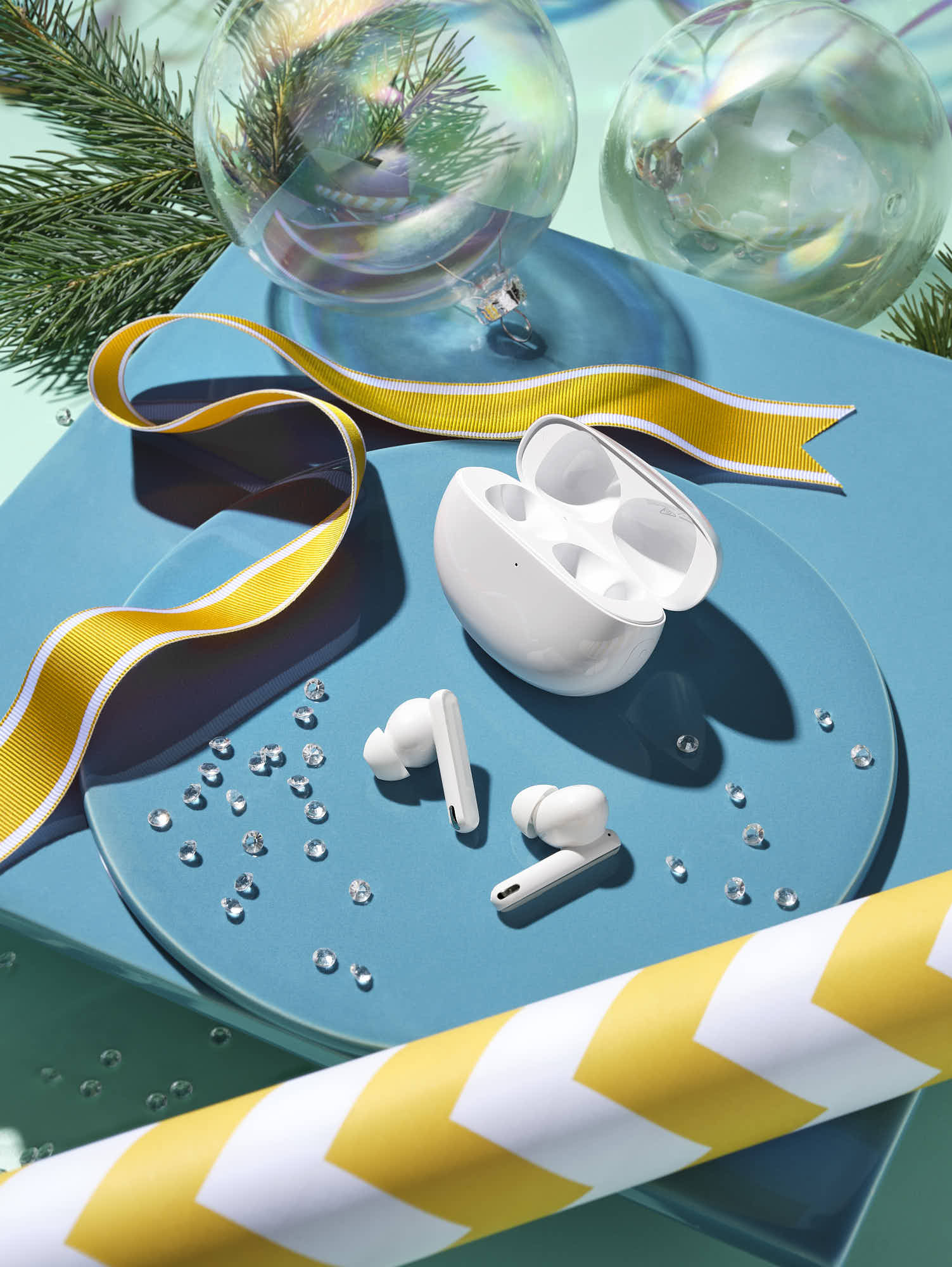 Wireless earbuds in open charging case with festive decorations and ribbon on blue background.
