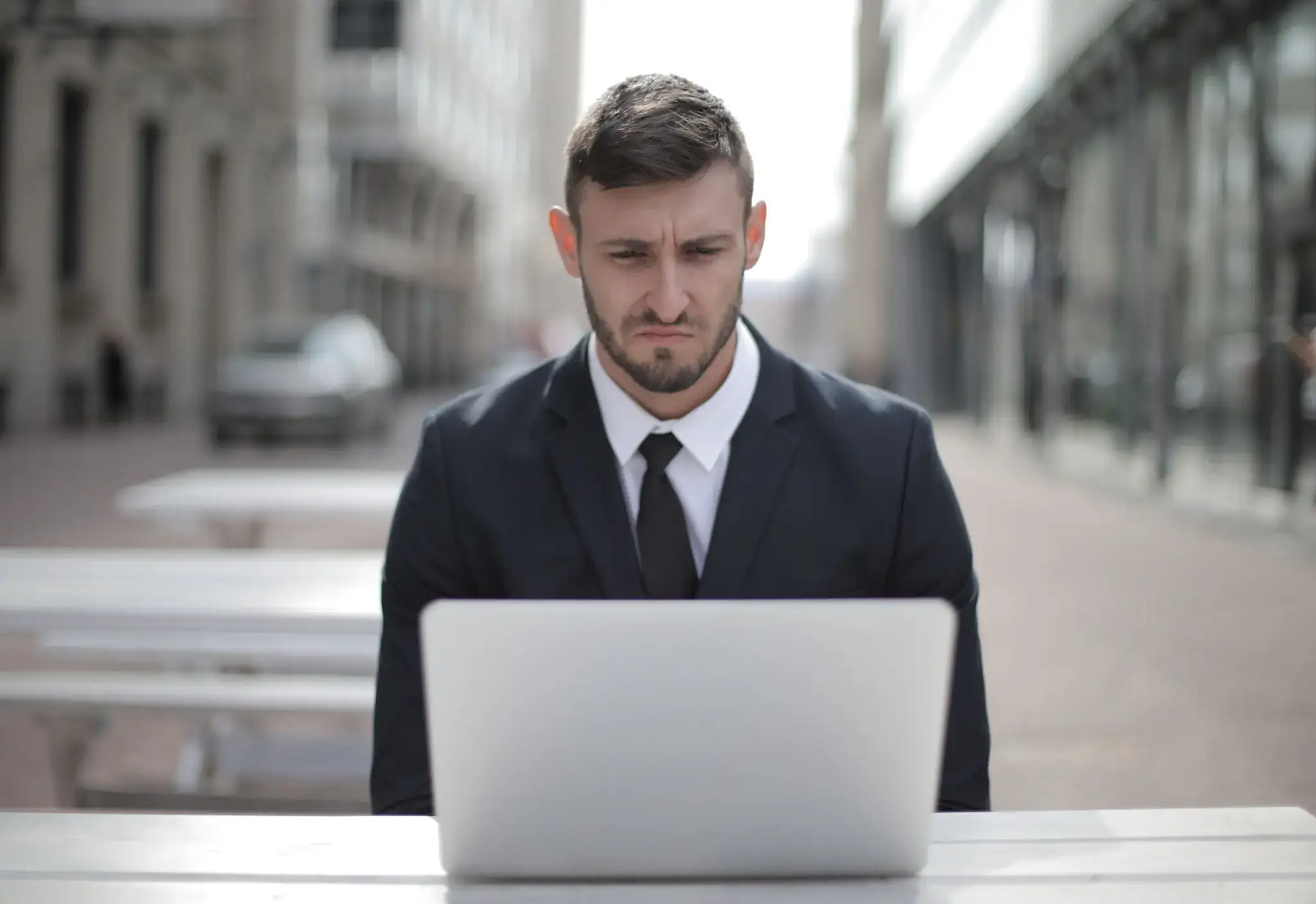 Frustrated businessman using a laptop outdoors, representing website problems and the need for professional web design and software development support