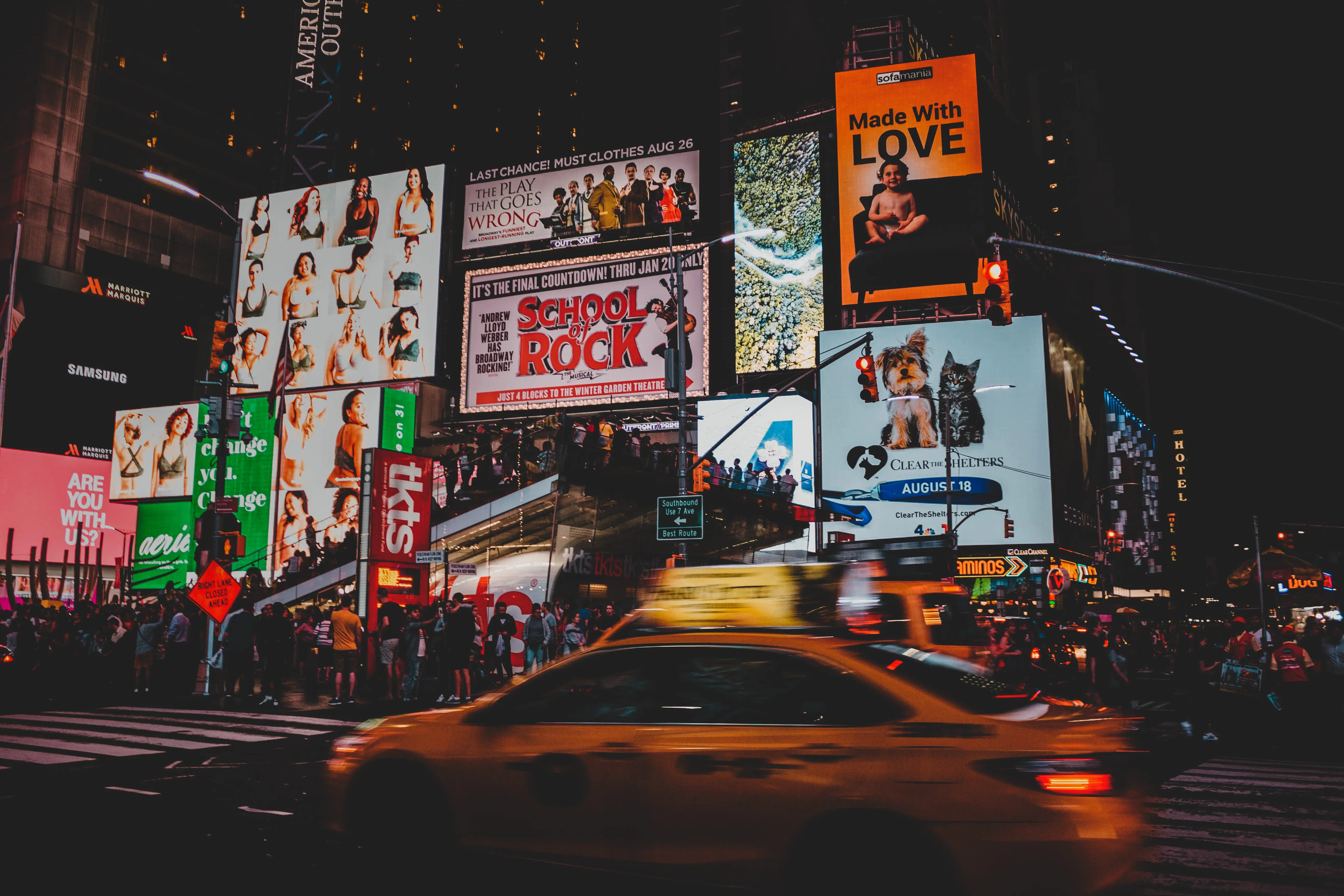 a man walking down a street past a large poster