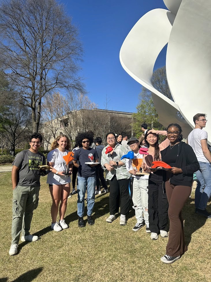 Man with glasses reviewing blueprints/papers at a cluttered desk.