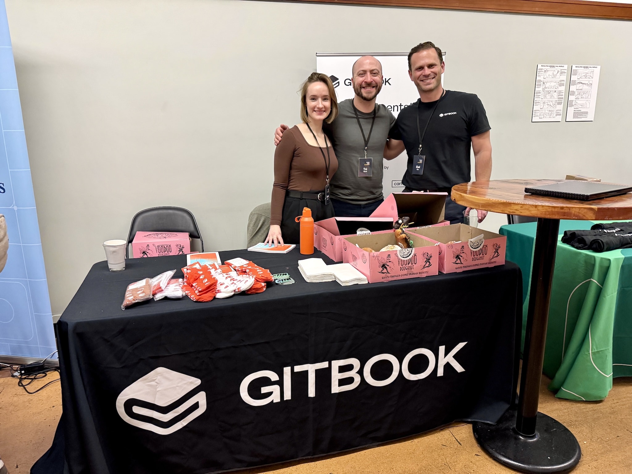 A photograph of Sarah, Tal and Elad from GitBook standing at the GitBook booth at WTD Portland 2026