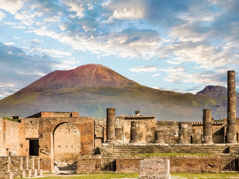 Mount Vesuvius rising behind the ancient ruins of Pompeii, illustrating the site destroyed by a powerful explosive volcanic eruption in 79 AD.