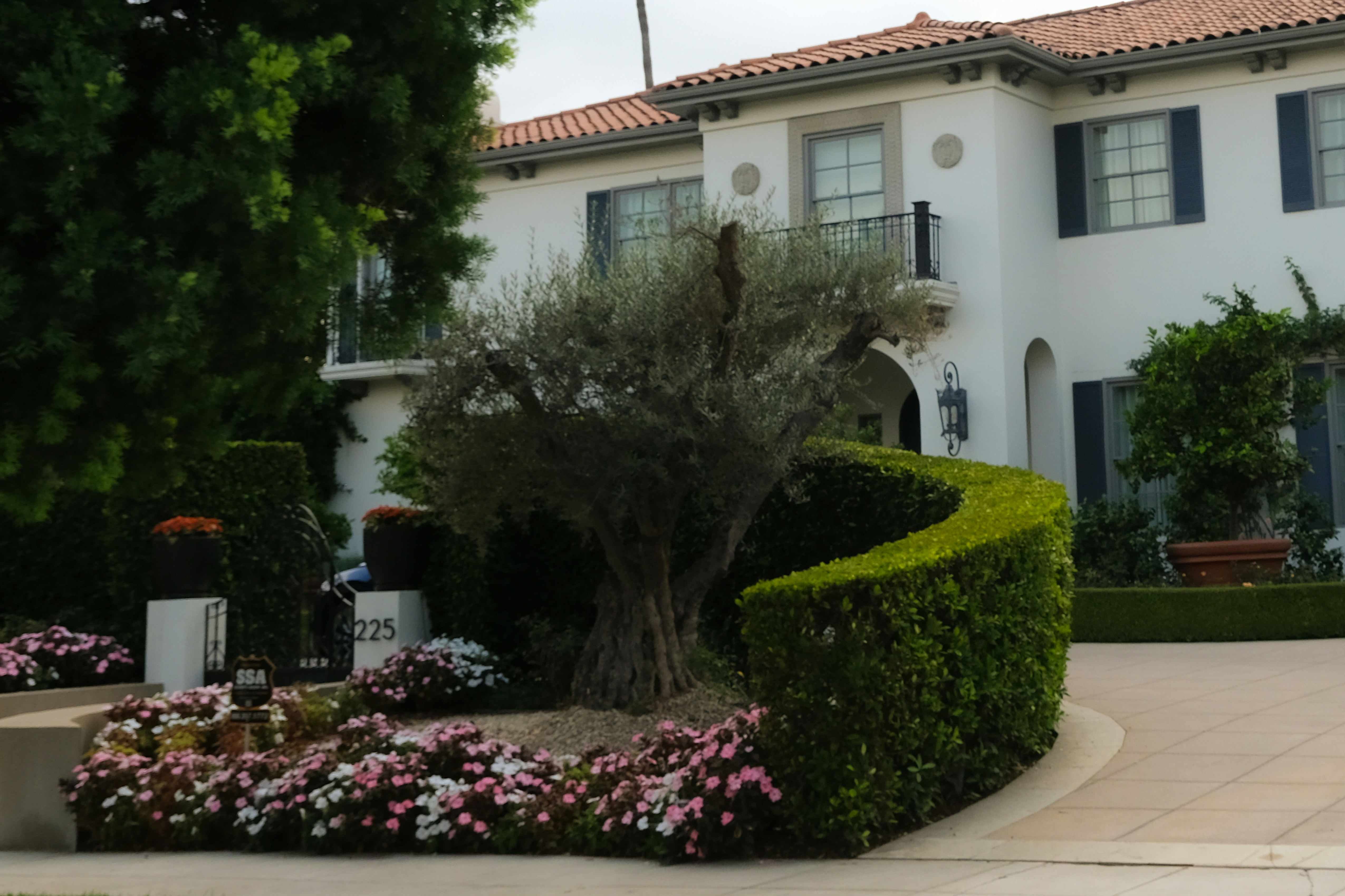 White mansion with manicured hedges and flowers.