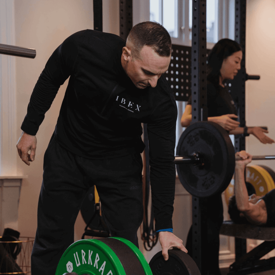 Instruktør justerer vekter hos Ibex Fitness på Vindern.