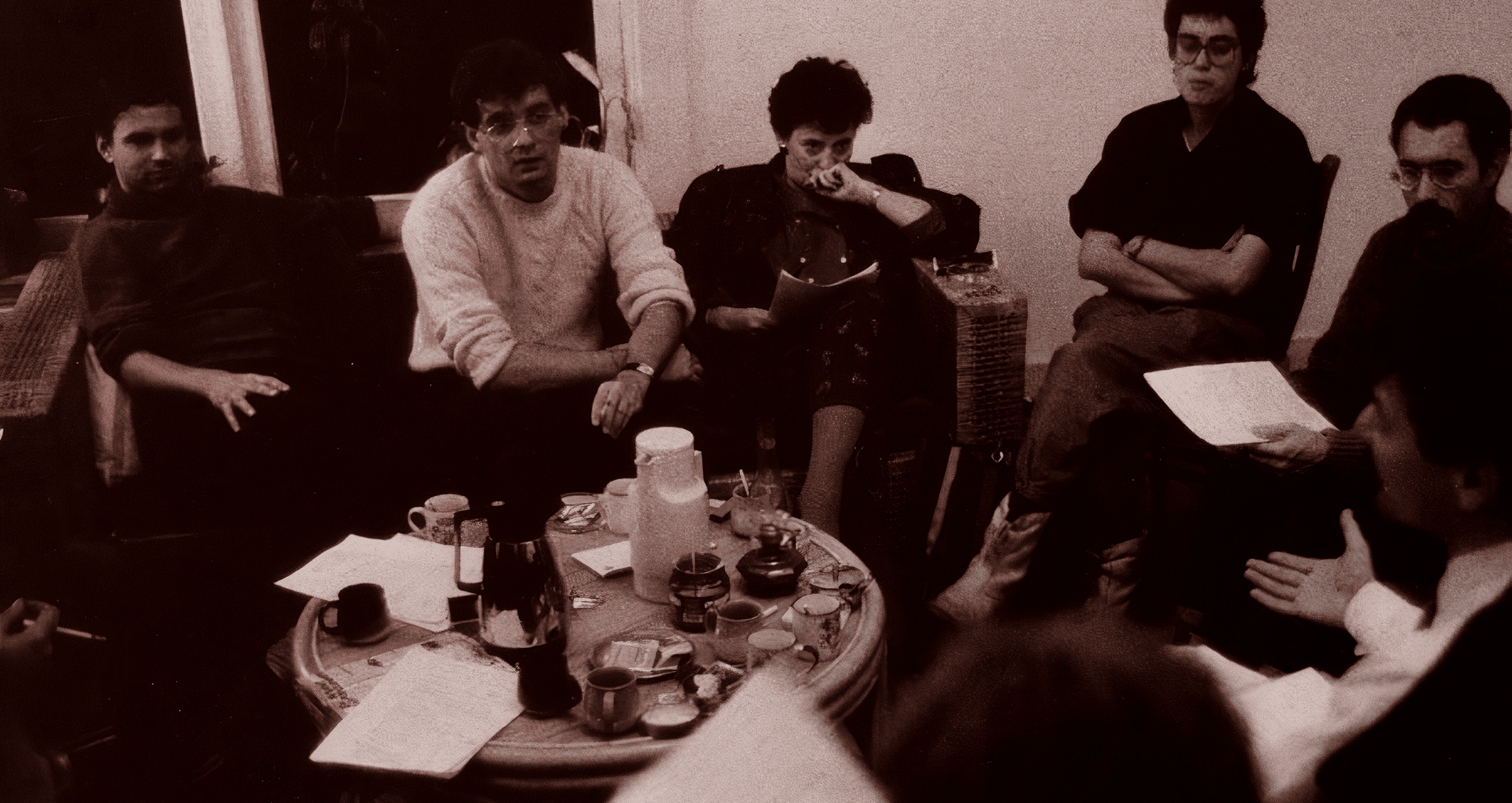 A group of six people poses on a city street, with buildings and shops visible in the background.