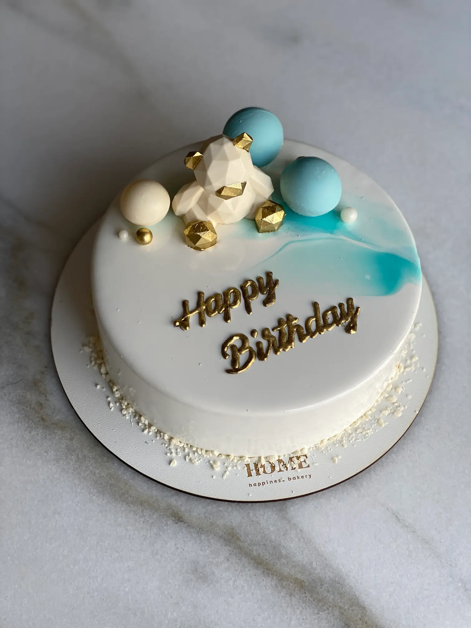 White round cake with "Happy Birthday" chocolate message and blue planets decoration
