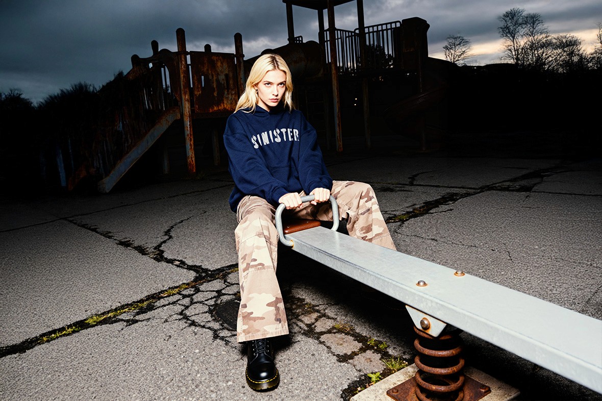 Model wearing navy oversized hoodie and baggy pants, Youth Distortion campaign photographed in a playground at night.